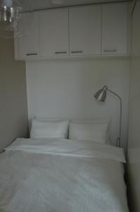 Cama blanca con lámpara y armarios blancos en Haven Homes, Aurora Haven, en Rovaniemi