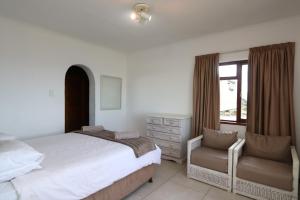 普利登堡灣的住宿－Villa Granada，卧室配有床、椅子和窗户。