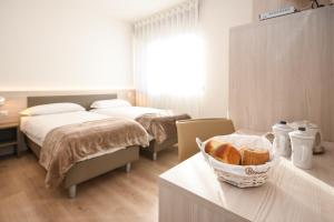 Habitación con 2 camas y mesa con una cesta de pan. en Residence Franca B&B, en Arco