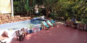 a man sitting at a table next to a swimming pool at Namaste Yoga Farm in Gokarna