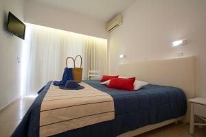 a bedroom with a bed with red and blue pillows at Kordistos Hotel in Kefalos
