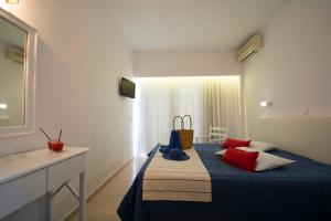 a bedroom with a bed with red and blue pillows at Kordistos Hotel in Kefalos