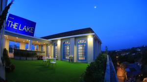 un edificio con un patio verde con mesa y sillas en The Lake Udon en Udon Thani