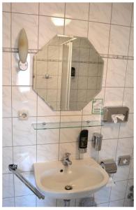 ein Bad mit einem Waschbecken und einem Spiegel in der Unterkunft Pension & Restaurant " Zum Harzer Jodlermeister" in Altenbrak