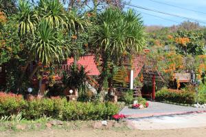 a garden with palm trees and flowers in front of a house at Phuphet Hill Resort in Phu Ruea