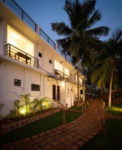 a building with a palm tree in front of it at de LAVENDER ac HOSTEL in Agonda +9 photos