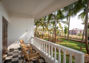 a balcony with a table and chairs and palm trees at de LAVENDER ac HOSTEL in Agonda