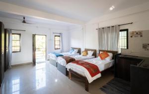 a bedroom with two beds and a desk and windows at de LAVENDER ac HOSTEL in Agonda