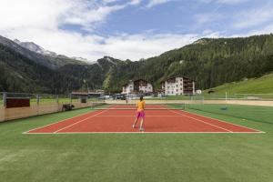 a person is standing on a tennis court at Kinder- & Gletscherhotel Hintertuxerhof in Tux