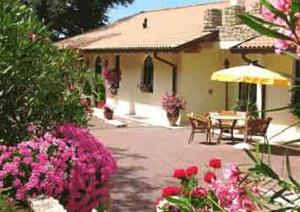 een patio met een tafel, een parasol en bloemen bij Villa Giada in Torri del Benaco