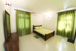 een slaapkamer met een bed en groene gordijnen bij 12 B Lewella Road, Kandy. in Kandy