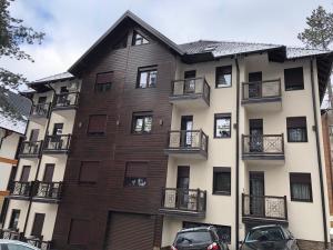 an apartment building with cars parked in front of it at S&M Apartmani Zlatibor in Zlatibor +3 photos