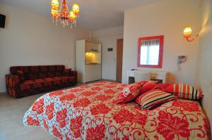 a bedroom with a red and white bed and a couch at CORALI STUDIOS in Chrysi Ammoudia