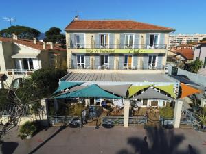 a building with tables and umbrellas in front of it at Hôtel du Bord de Mer "Le Vanillé" in Cagnes-sur-Mer