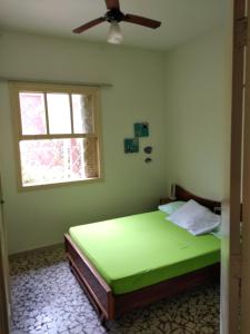 a bedroom with a green bed with a ceiling fan at Casas em Ubatuba in Ubatuba