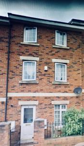 a brick house with a white door and three windows at The Townhouse Newcastle in Newcastle upon Tyne