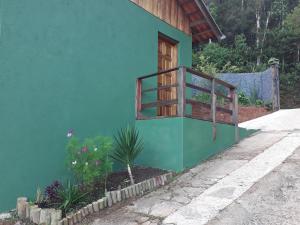 ein blaues Gebäude mit einem Fenster und einer Pflanze in der Unterkunft Casa Estilo Kitnet in Campos do Jordão