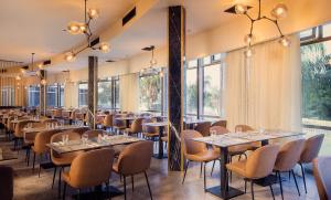 a restaurant with tables and chairs and large windows at Hotel Lake House Kinneret in Tiberias