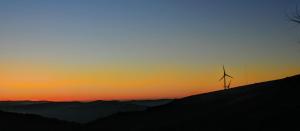 uma turbina eólica no topo de uma colina ao pôr-do-sol em Miradouro da Branda em Branda de Santo António