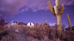 a desert with a cactus and a white building at night at Observatorio Ampimpa in Amaicha del Valle