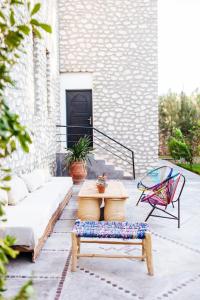 eine Terrasse mit einem Sofa, einem Tisch und Stühlen in der Unterkunft La Maison des Ailleurs in Essaouira