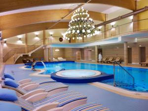 einen großen Pool mit Stühlen und einem Kronleuchter in der Unterkunft Hotel Mercure Krynica Zdrój Resort&Spa in Krynica-Zdrój