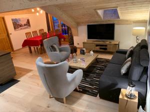 ein Wohnzimmer mit Sofa, Sesseln und Fernseher in der Unterkunft Arc 1950 - derniére étage in Arc 1950