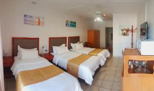 um quarto de hotel com três camas e uma televisão em hotel pension steiner em Windhoek