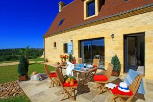 een terras met een tafel en stoelen en een huis bij La Malonie in Sarlat-la-Canéda