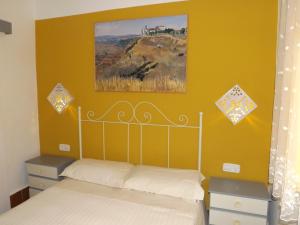 una camera da letto con un letto con una parete gialla di Casa Rural La Alfarera a Corral de Calatrava