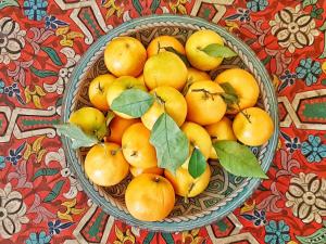 a bowl of oranges with green leaves on a table at Riad Dar Rita in Ouarzazate