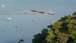 a dock in the middle of the water with boats at Oré Suítes e Chalés in Ubatuba