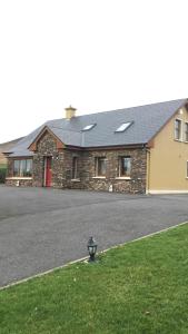 a brick house with a black roof and a street at Gort a Phump in Ballydavid
