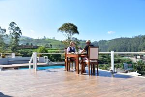 two people sitting at a table on a roof at Hilldale Retreat in Nuwara Eliya