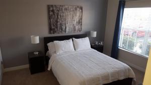 ein Schlafzimmer mit einem Bett mit weißer Bettwäsche und einem Fenster in der Unterkunft 4 Bedroom Private Lakefront Town Home at Storey Lake near Disney World Parks in Kissimmee + 49 Fotos