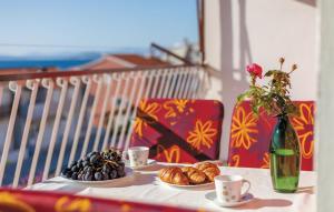 a table with two plates of food and a vase with flowers at Apartman Marta in Podstrana
