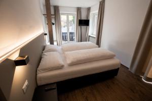 a small bed in a room with a window at Rider Hotel Obereggen in Obereggen