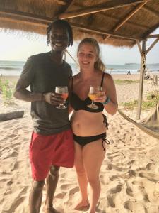 a man and woman standing on the beach holding wine glasses at Bees Mouth Gambia in Sanyang