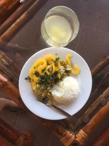 a plate of food with rice and a glass of water at Bees Mouth Gambia in Sanyang +23 photos