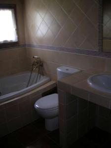 a bathroom with a toilet and a tub and a sink at Casa Feixas in Gistaín