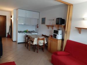 eine Küche und ein Esszimmer mit einem Tisch und einem roten Sofa in der Unterkunft Monolocale a Passo Tonale in Passo del Tonale