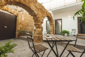 d'une terrasse avec une table, des chaises et un mur en briques. dans l'établissement Cortile Baronello, à Agrigente