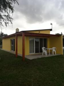 a yellow house with a table and two chairs at Departamento Teodelina in Quehué