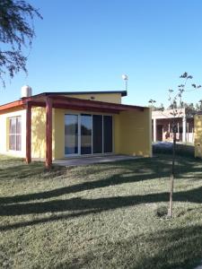 a small yellow house in a yard with a tree at Departamento Teodelina in Quehué