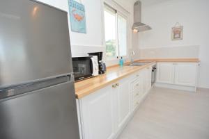 a kitchen with white cabinets and a stainless steel refrigerator at Pura Vida El Morche in Torrox Costa