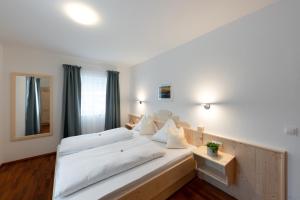 1 dormitorio con 1 cama blanca grande con almohadas blancas en Wawies Apartments en Flachau