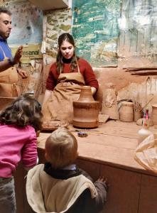 a woman and children making pottery in a workshop at La Casa del Alfarero - Mejor Villa Sostenible de Europa in Úbeda