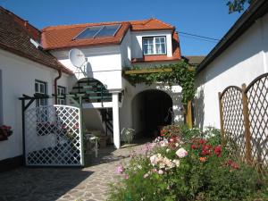 ein weißes Haus mit einem Tor und ein paar Blumen in der Unterkunft Weinhof Gregor Raab in Unterretzbach