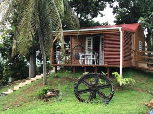 a wooden cabin with a wheel in front of it at Charmant bungalow au cœur de l’île in Baie-Mahault