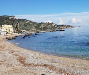 a beach with a rocky shoreline and the ocean at TH LUXURY SUITE in Giardini Naxos